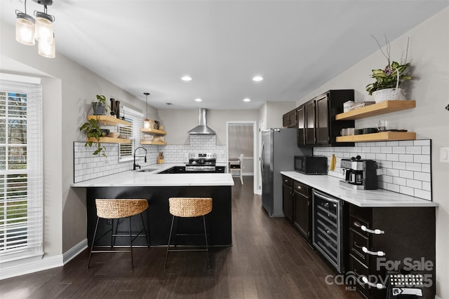 kitchen featuring stainless steel appliances, a sink, wall chimney exhaust hood, and open shelves