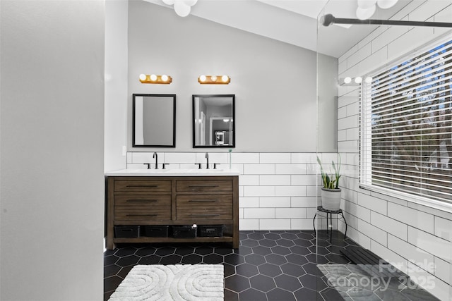 full bath with lofted ceiling, a sink, tile walls, tile patterned floors, and double vanity