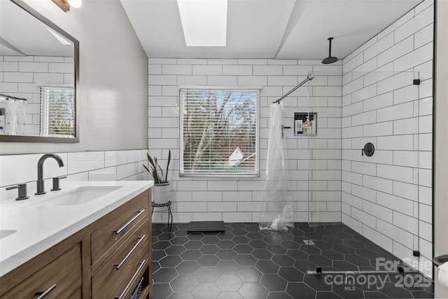 full bathroom with tile walls, a healthy amount of sunlight, a tile shower, and vanity