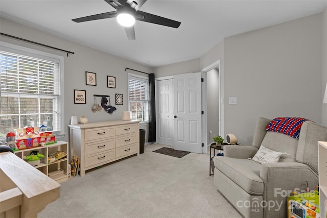 living area featuring plenty of natural light, ceiling fan, and light colored carpet