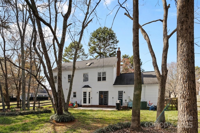 view of front facade featuring a chimney, fence, cooling unit, a patio area, and a front yard