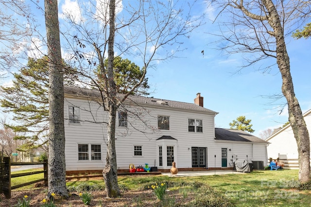 back of house with a lawn, a chimney, fence, central air condition unit, and a patio area