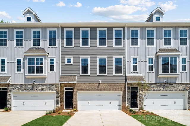 multi unit property featuring driveway, stone siding, board and batten siding, and brick siding