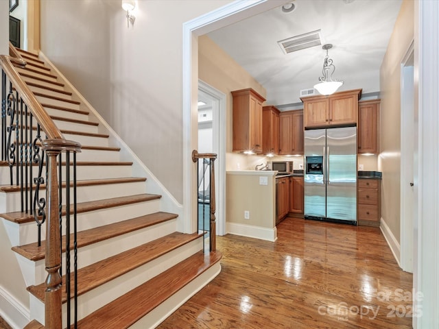 kitchen featuring brown cabinets, decorative light fixtures, visible vents, appliances with stainless steel finishes, and wood finished floors