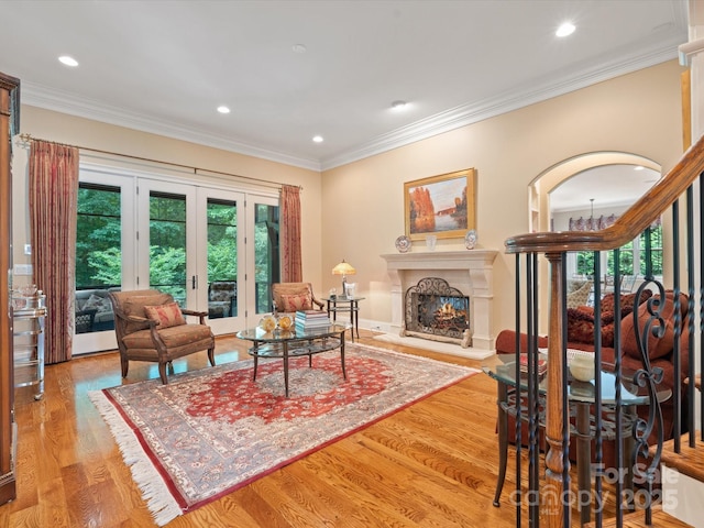 living room with light wood-type flooring, a lit fireplace, and ornamental molding