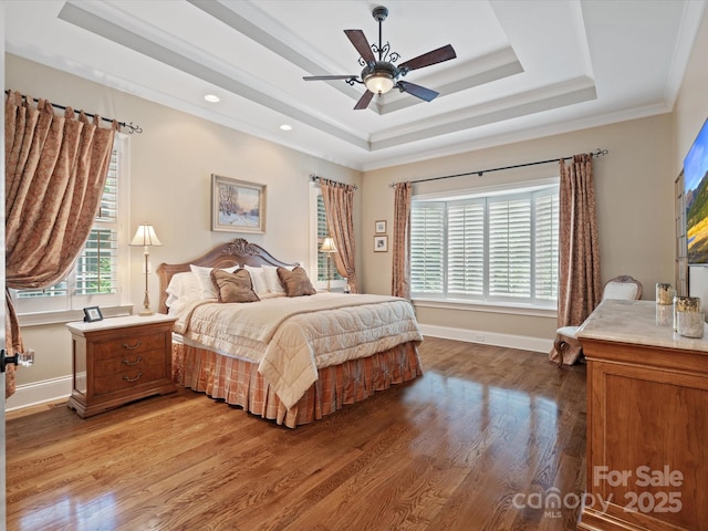 bedroom with ornamental molding, a tray ceiling, wood finished floors, and baseboards