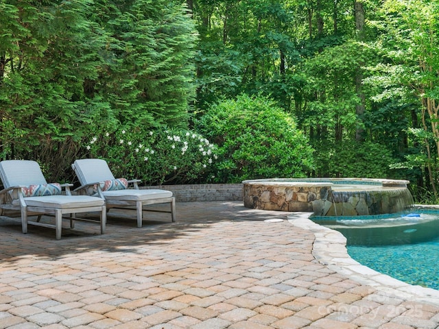 view of patio / terrace with a pool with connected hot tub