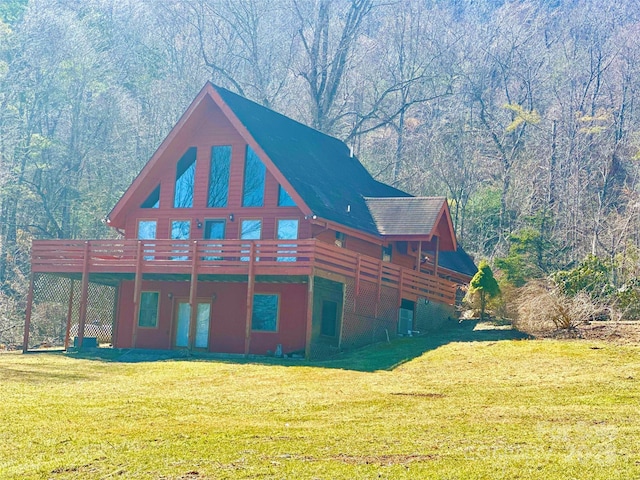 view of side of property with a deck, a view of trees, and a yard