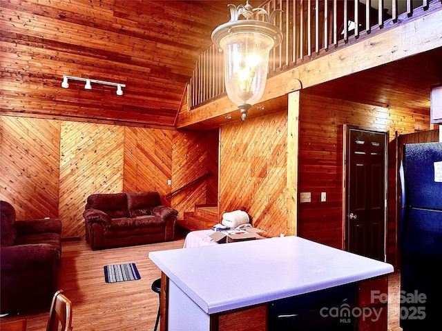 kitchen with a notable chandelier, wood walls, freestanding refrigerator, a center island, and track lighting