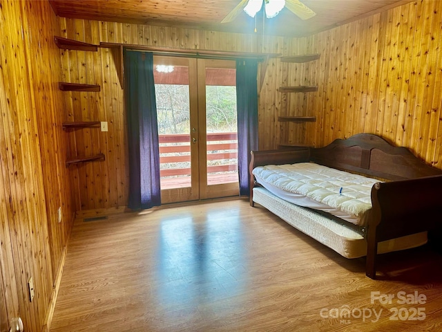 bedroom with access to outside, french doors, wood finished floors, and wooden walls