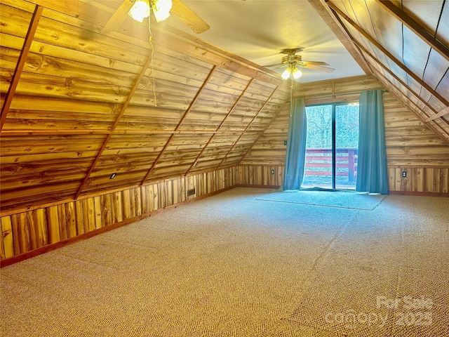 additional living space featuring lofted ceiling, wood walls, ceiling fan, and carpet floors