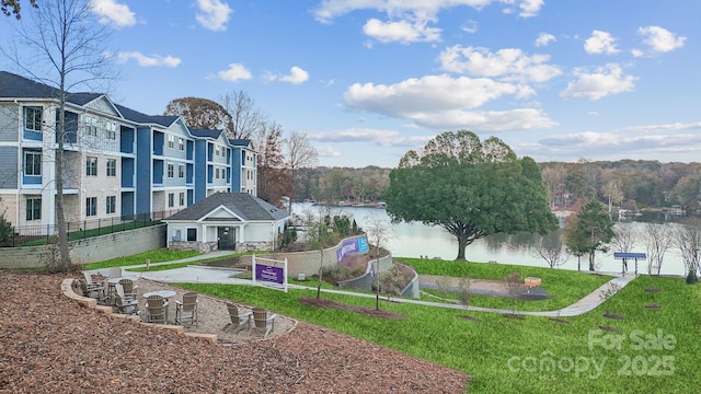 surrounding community featuring a water view, a yard, and fence