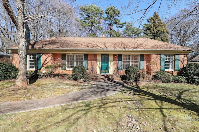 ranch-style house with a front lawn, a shingled roof, and brick siding