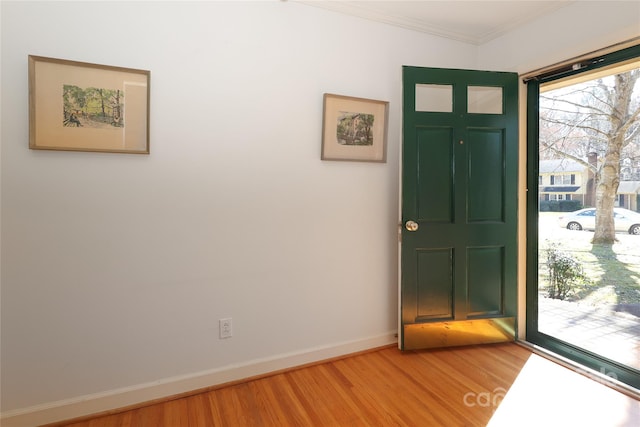 entryway with light wood-style floors, baseboards, and crown molding