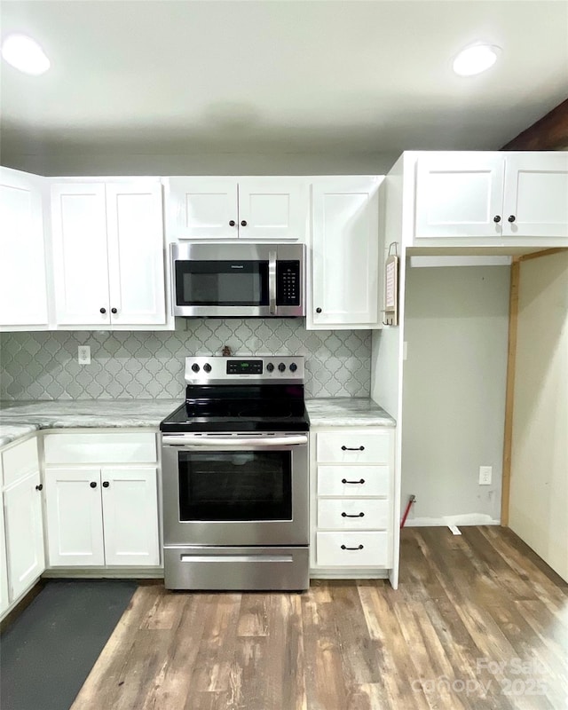 kitchen with white cabinets, light stone countertops, tasteful backsplash, and stainless steel appliances