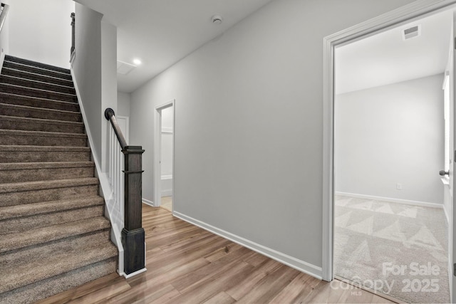 staircase featuring visible vents, baseboards, and wood finished floors