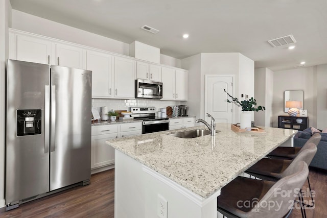 kitchen with appliances with stainless steel finishes, a center island with sink, and white cabinets