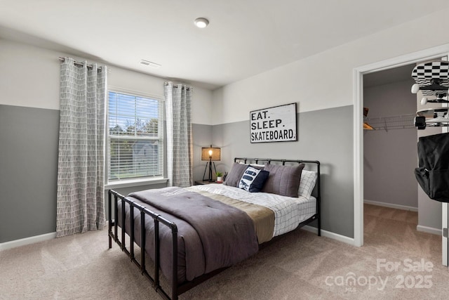 carpeted bedroom featuring a spacious closet, visible vents, and baseboards