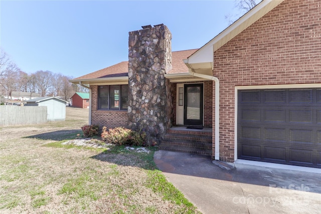 view of front of house with an attached garage, brick siding, fence, a front lawn, and a chimney