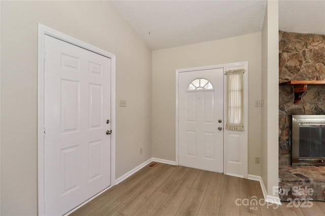 entrance foyer featuring light wood-type flooring, baseboards, a fireplace, and heating unit