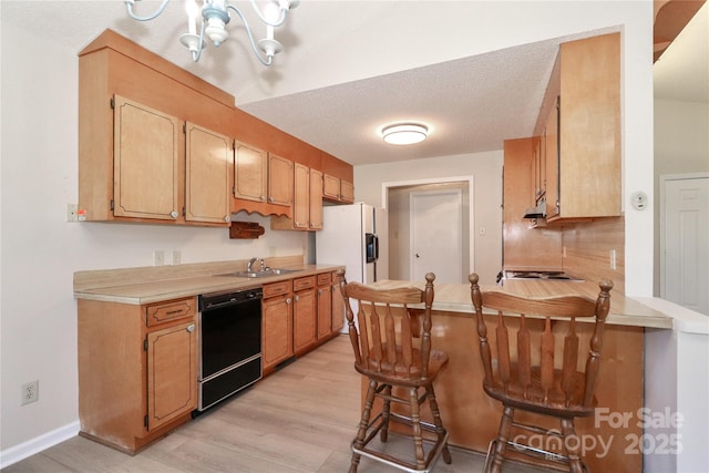 kitchen featuring black dishwasher, light countertops, a breakfast bar, and a peninsula