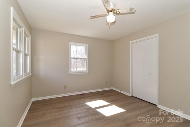 empty room with ceiling fan, baseboards, and wood finished floors