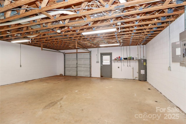 garage featuring concrete block wall, electric panel, and water heater