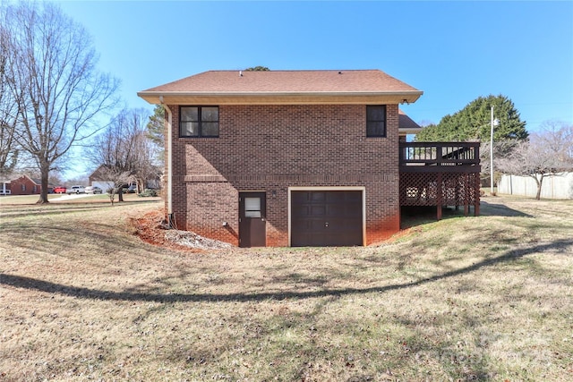 back of property featuring a garage, a yard, a deck, and brick siding