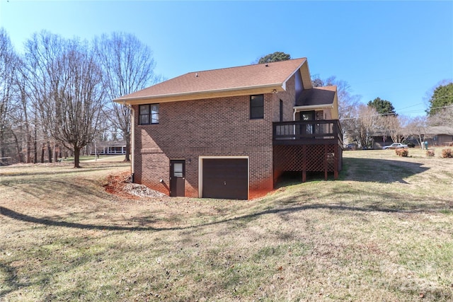 back of house featuring a yard, brick siding, an attached garage, and a wooden deck