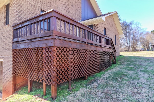 view of property exterior featuring brick siding, a yard, and a wooden deck