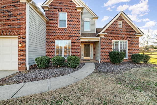 traditional home featuring a garage and brick siding