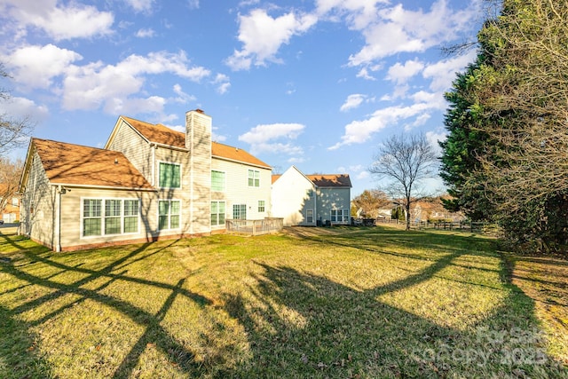 back of property with a lawn, a chimney, and fence