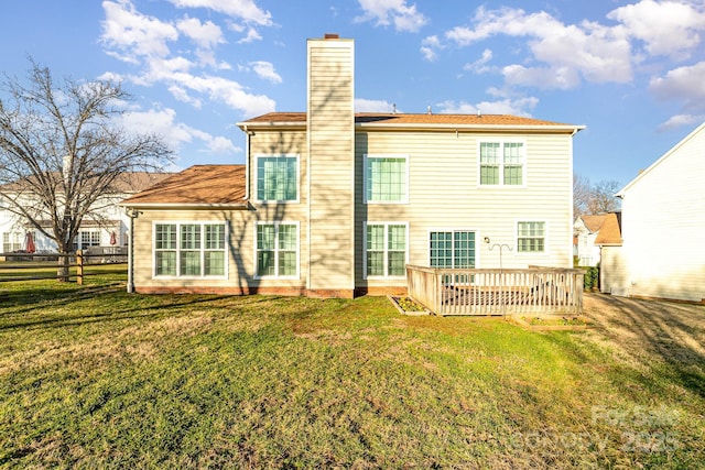 back of property with a lawn, a chimney, a wooden deck, and fence