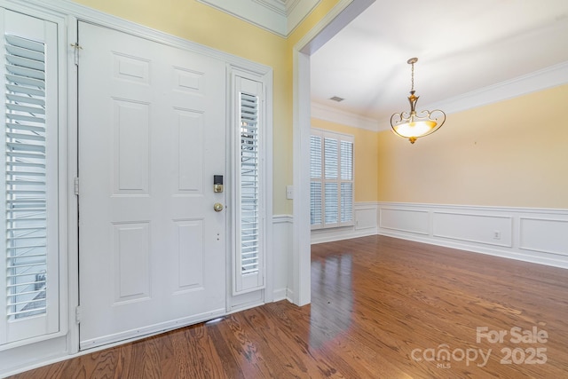 entryway with a wainscoted wall, visible vents, ornamental molding, and wood finished floors