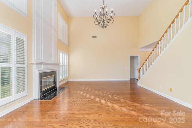 unfurnished living room with stairway, a fireplace, wood finished floors, and baseboards