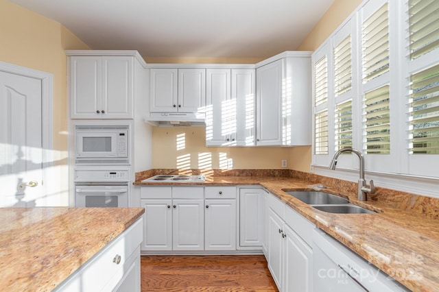 kitchen with white appliances, a sink, white cabinets, and under cabinet range hood