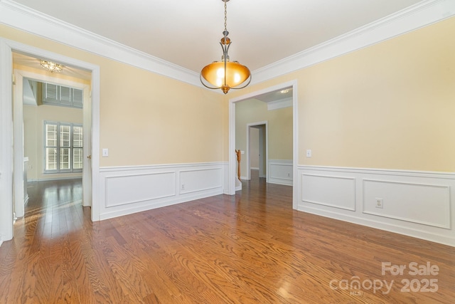 empty room with ornamental molding and wood finished floors