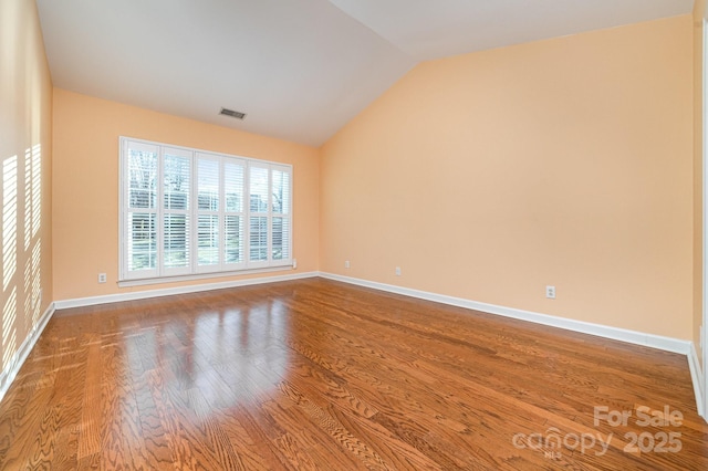 unfurnished room with lofted ceiling, visible vents, baseboards, and wood finished floors