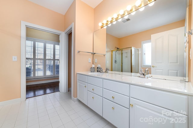 bathroom featuring a stall shower, tile patterned flooring, a sink, and visible vents