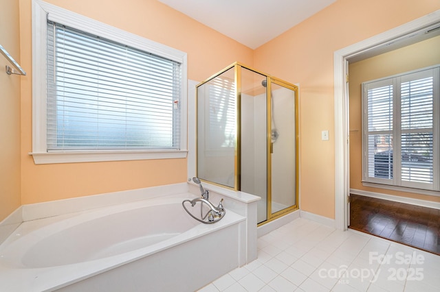 bathroom with a stall shower, tile patterned flooring, baseboards, and a bath