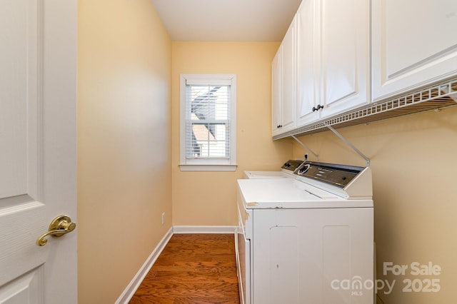 clothes washing area featuring dark wood-style floors, washer and clothes dryer, cabinet space, and baseboards