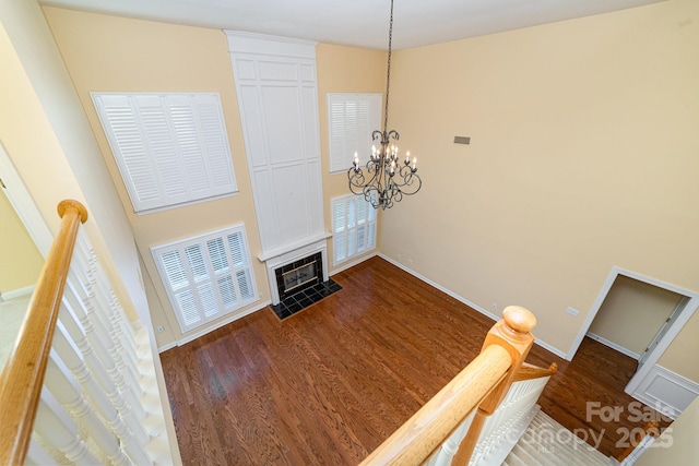 living area featuring dark wood-style floors, baseboards, a fireplace with flush hearth, and a chandelier