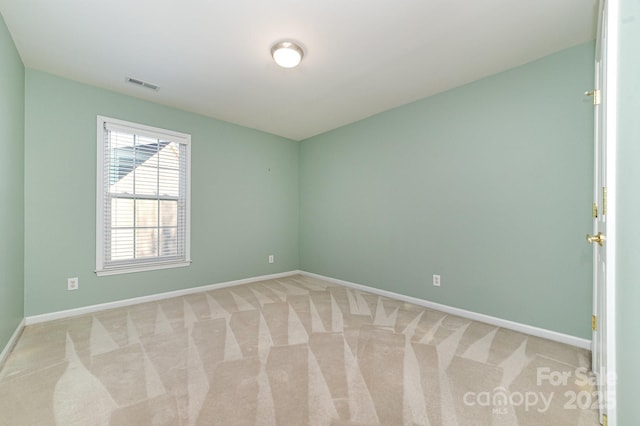 empty room featuring light colored carpet, visible vents, and baseboards