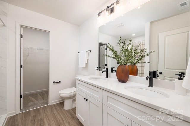 bathroom with toilet, double vanity, visible vents, and a sink