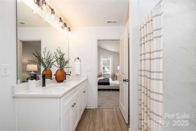 bathroom with wood finished floors, a sink, visible vents, and connected bathroom