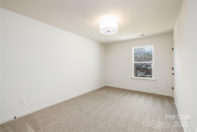 empty room featuring baseboards, visible vents, and light colored carpet