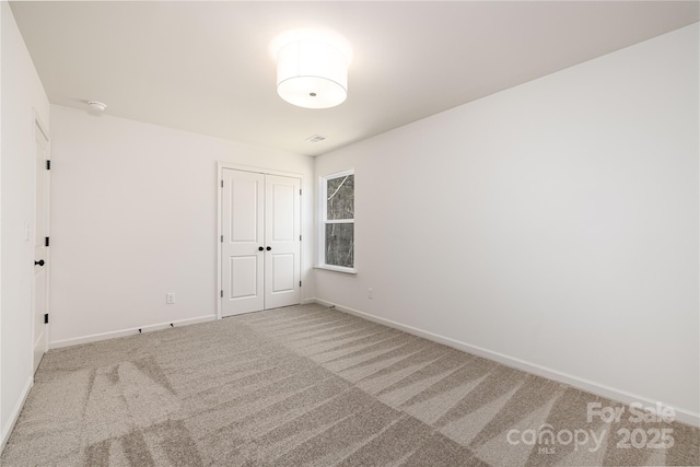 spare room featuring carpet, visible vents, and baseboards