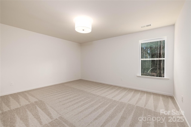 carpeted spare room featuring visible vents and baseboards