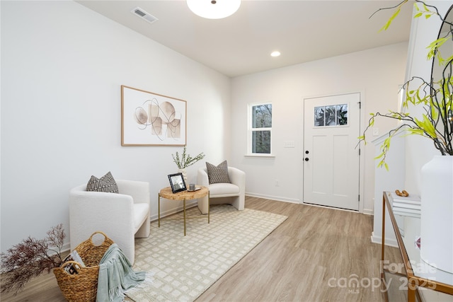 living area with baseboards, light wood-type flooring, visible vents, and recessed lighting