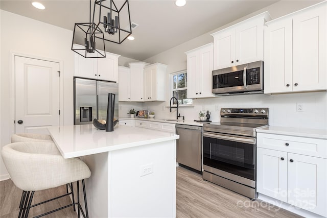 kitchen featuring appliances with stainless steel finishes, a kitchen island, backsplash, and white cabinetry